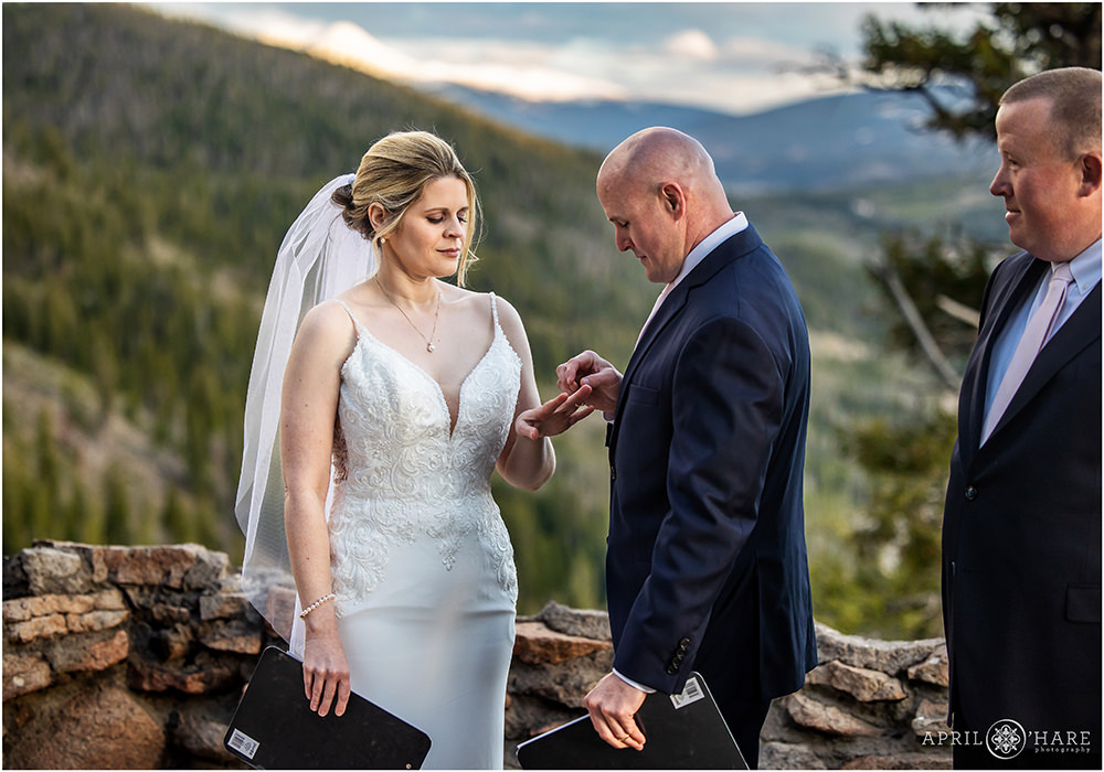 Groom puts wedding ring on his wife's finger at Sapphire point in Colorado