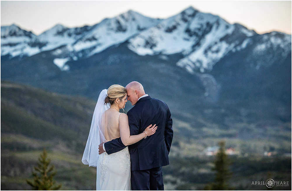 Couple lean into each other with a gorgeous mountain backdrop behind them at Sapphire Point in Colorado