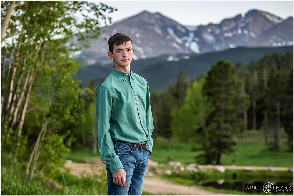 High school senior boy poses at Wind River Ranch during his family vacation in Estes Park with Longs Peak backdrop