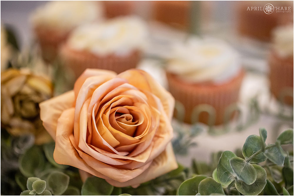 Detail photo of the silk flowers decorating the dessert table with cupcakes in the backdrop at a vow renewal party in Colorado