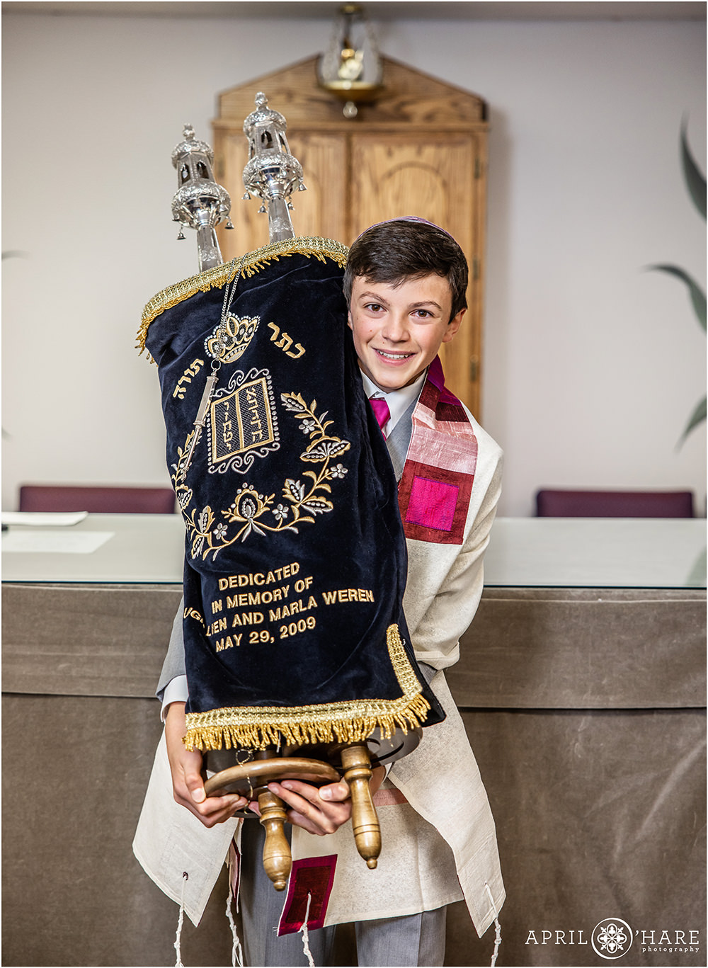 Bar Mitzvah boy holds torah for a posed photo prior to his service