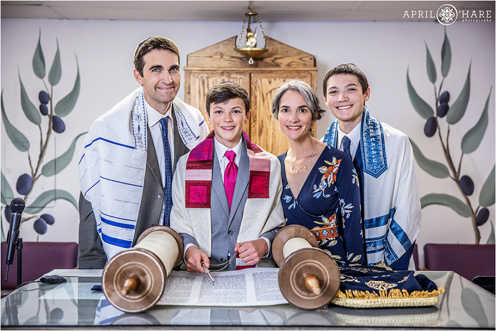 Family of four with two teenage sons poses with the torah at their son's bar mitzvah