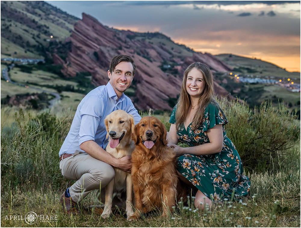 Couple photographed at sunset with their two sweet dogs with Red Rocks at Sunset in the backdrop in Colorado