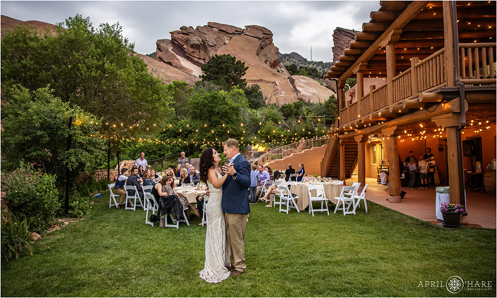 Couple dance on the lawn under the string lights at Red Rocks Trading Post Backyard wedding in Colorado