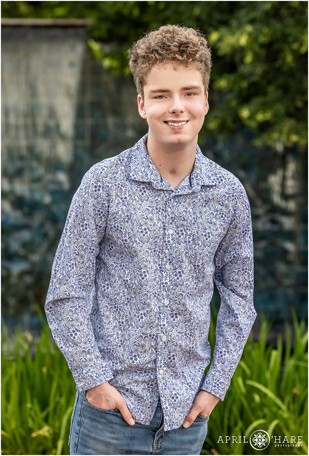 Young senior wearing a fun blue and white print button down shirt at his senior photography session at Denver Botanic Gardens