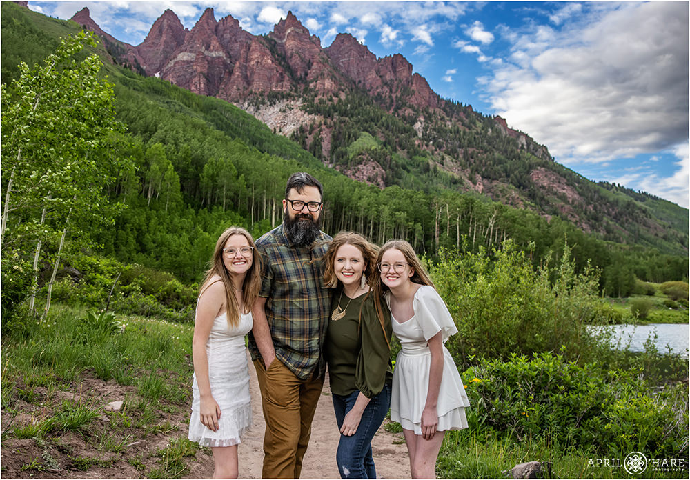 Cute family of 4 with two daughters wearing white in front of the incredible nature at Maroon Bells in Colorado