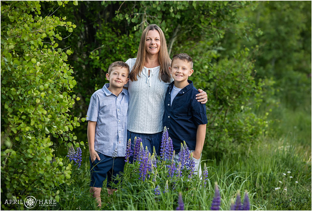 Mother stands with her two sons in a pretty mountain garden in Colorado