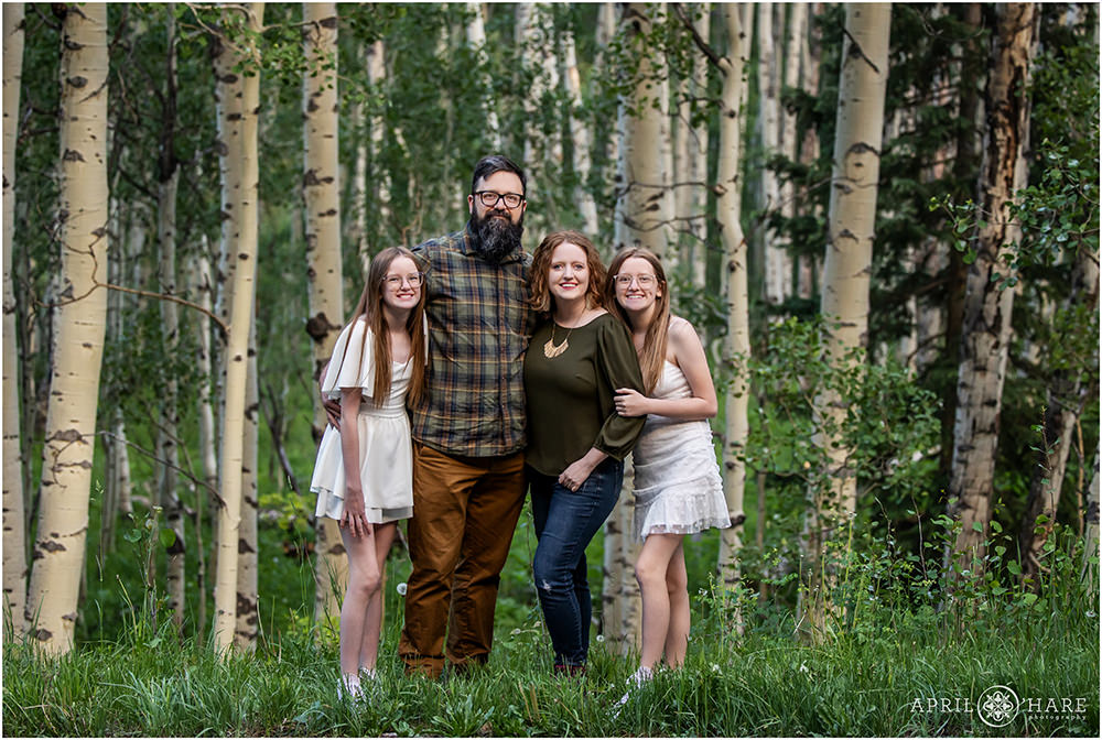 A family of four pose with layered aspen trees near Maroon Bells in Aspen Colorado