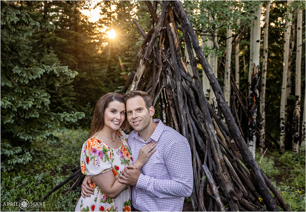 Pretty backlight in a couple portrait with a wood tipi structure in Colorado