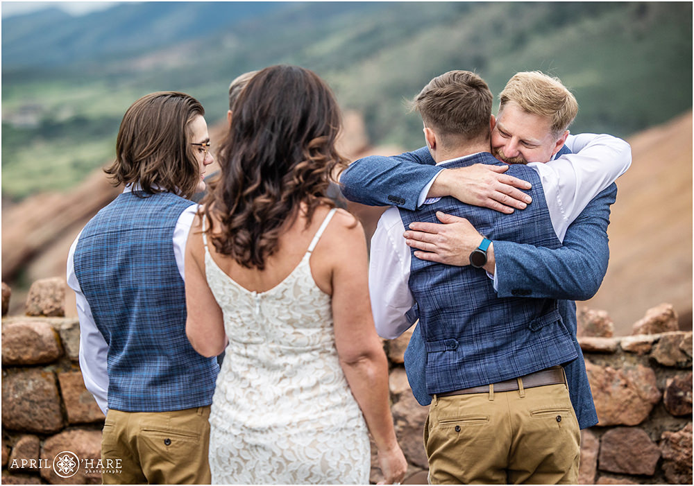 Groom hugs his son in law after he walks his mom down the aisle at Red Rocks