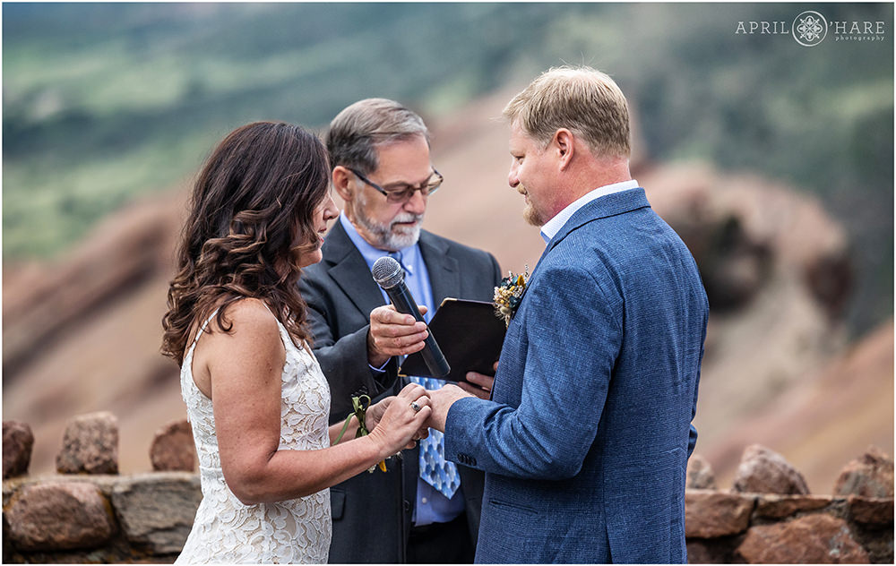 Bride and groom exchange rings at their Red Rocks wedding in Colorado