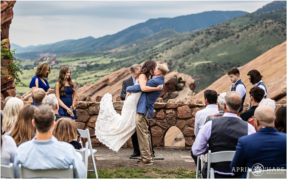 Groom picks up his bride for their first kiss at Red Rocks Trading Post