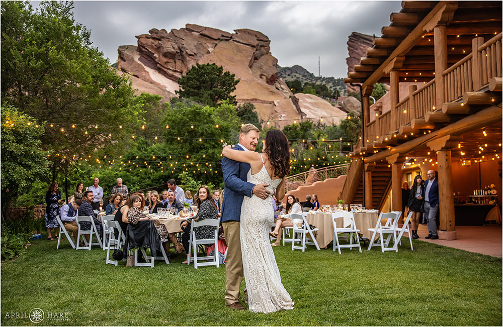Bride and groom dance under the string lights on a stormy summer evening at their Red Rocks wedding
