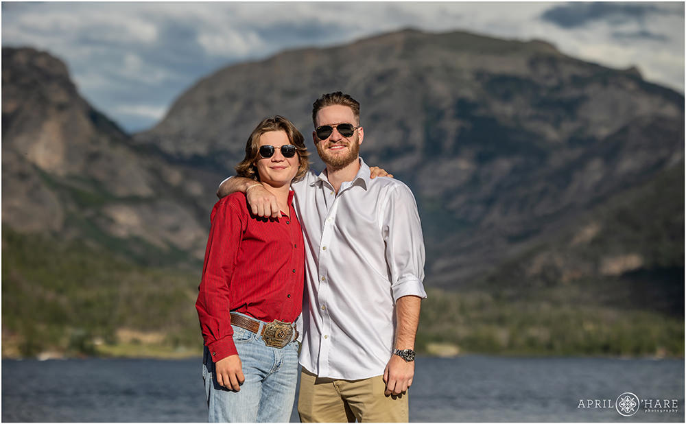 Two brothers side hug while wearing sunglasses with mountain backdrop in Grand Lake Coloradao