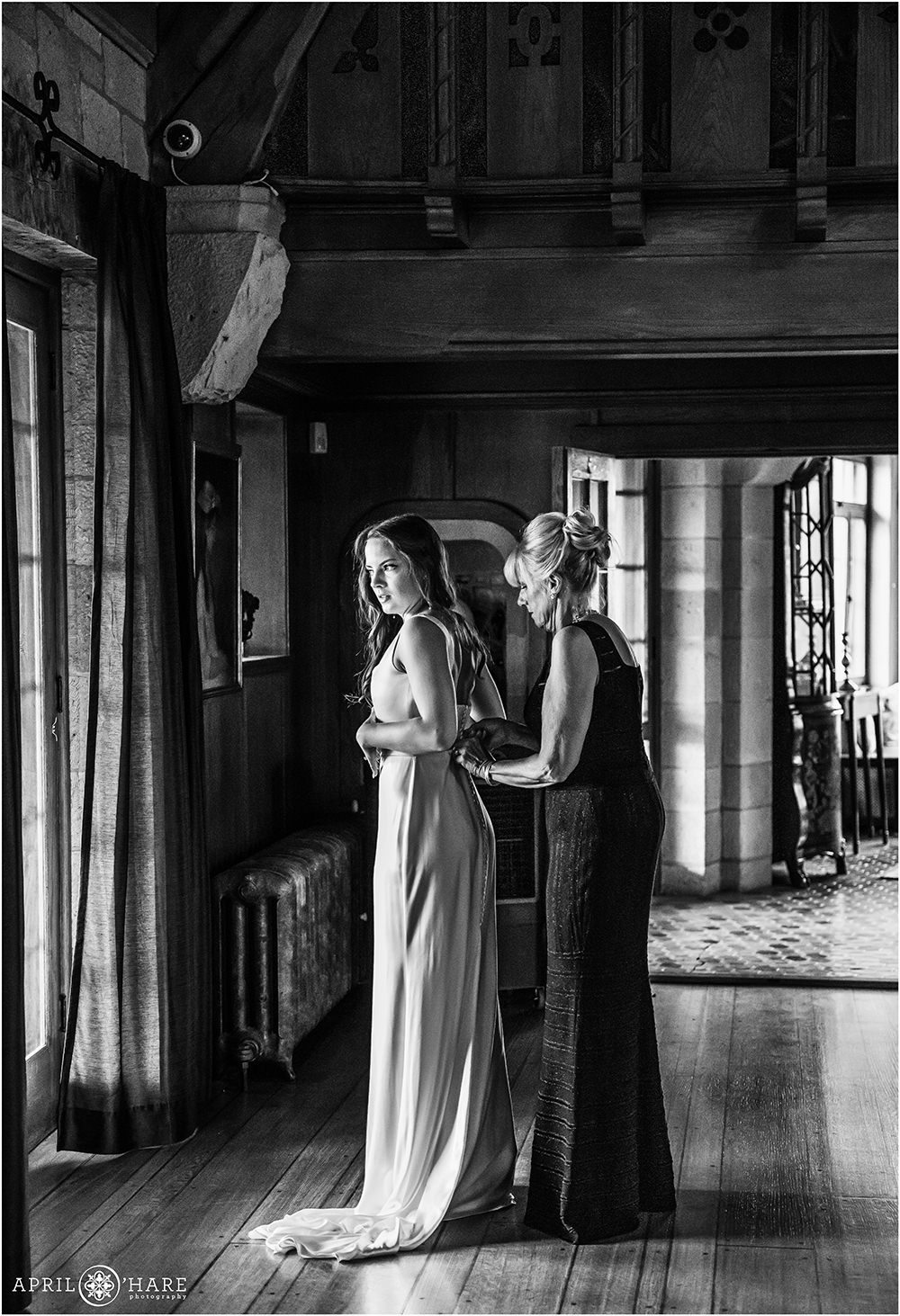 B&W Photo of Bride getting help with her dress from her mom at Castle Wedding in CO