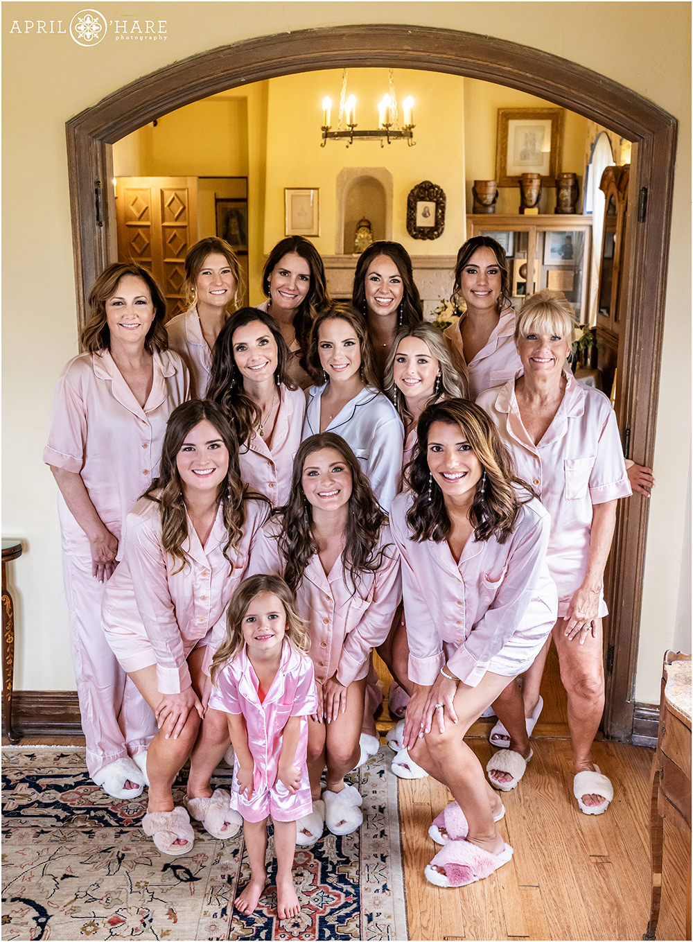 Bride surrounded by her family and friends all wearing matching pink silk pjs at a historic Castle wedding in Colorado