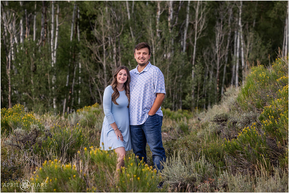 Cute couple wearing shades of blue pose with some aspen trees in the backdrop in Summit County Colorado