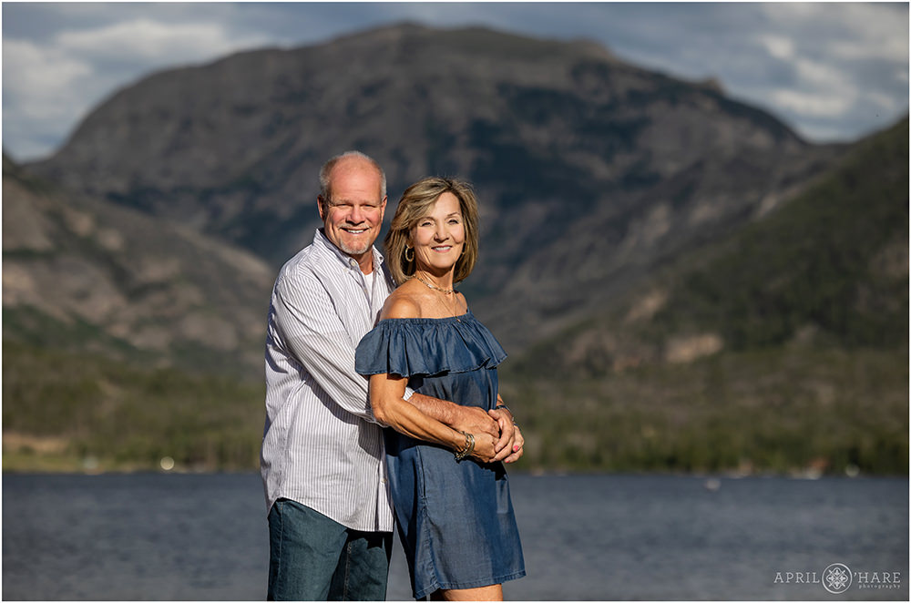 Couple wearing shades of blue pose in front of Grand Lake in Colorado