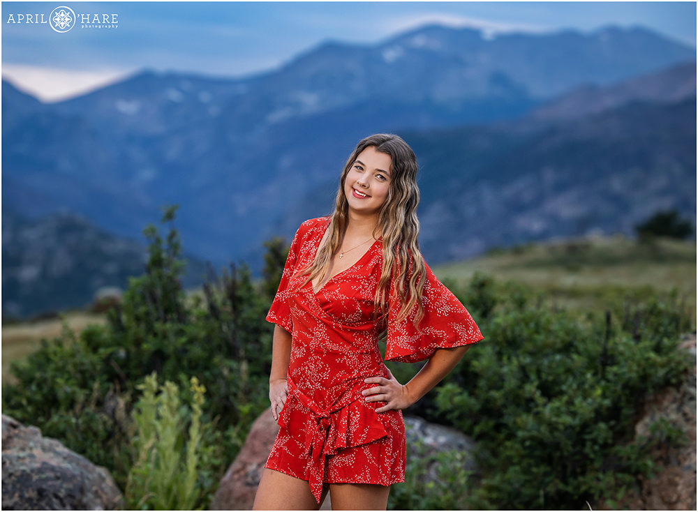 Beautiful senior girl wearing red romper with a mountain backdrop at Rocky Mountain National Park in Estes Park