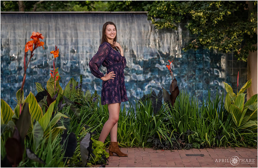 Beautiful senior girl wearing short brown boots with a pretty purple floral dress at Denver Botanic Gardens