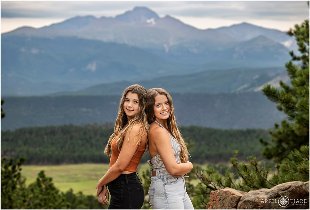 Two high schoolr best friends pose at Rocky Mountain National Park with Longs Peak in the distance