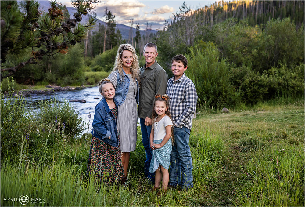 Adorable family of 5 stand in front of a river backdrop in Grand Lake Colorado