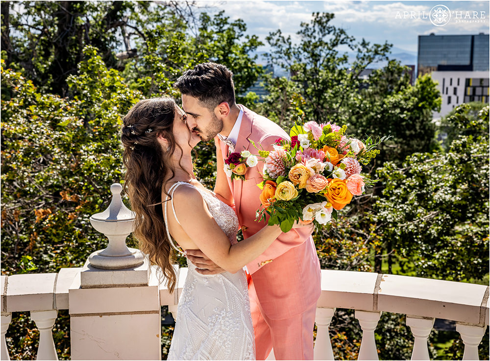 Couple kiss after their first look on the balcony at Grant-Humphreys Mansion in Denver