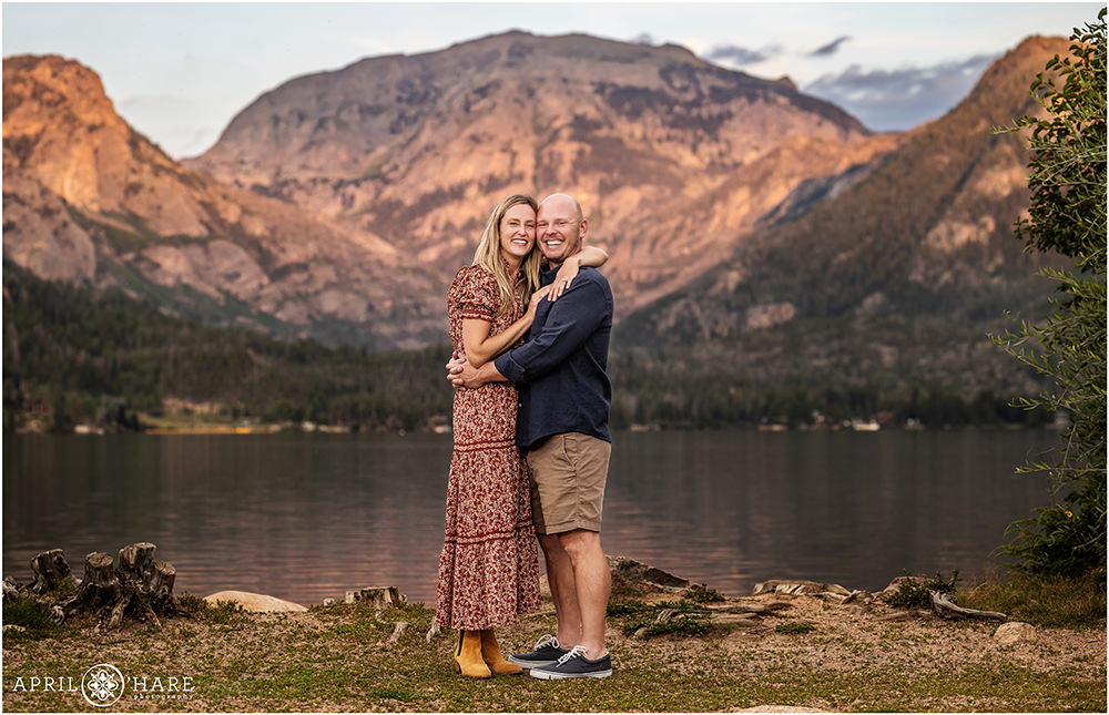 Sweet photo of a couple hugging in front of a pretty sunset mountain backdrop in Grand Lake Colorado