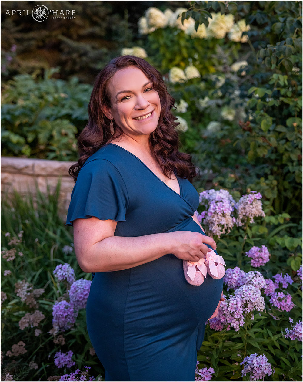 Mama to be photographs with cute pink baby shoes at her maternity photography session at Denver Botanic Gardens