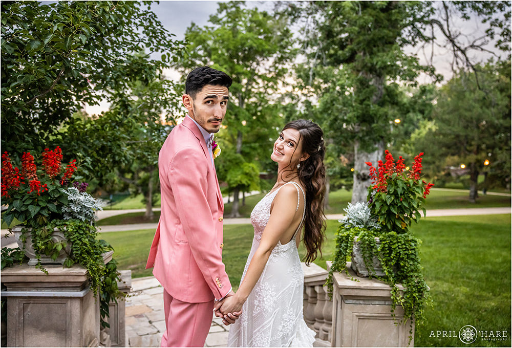 Couple pose for a fun photo looking over their shoulder on the steps next to the garden at Grant-Humphreys Mansion in Denver