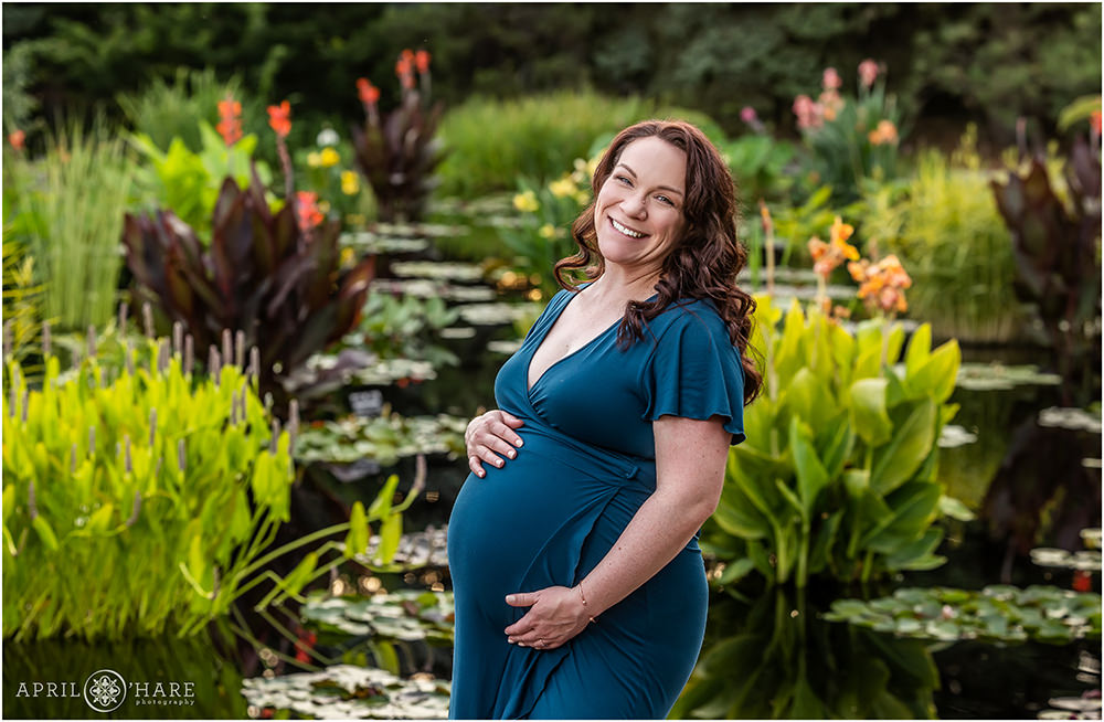 Gorgeous mom is photographed in a dark teal blue dress in front of the water lily garden at Denver Botanic Gardens