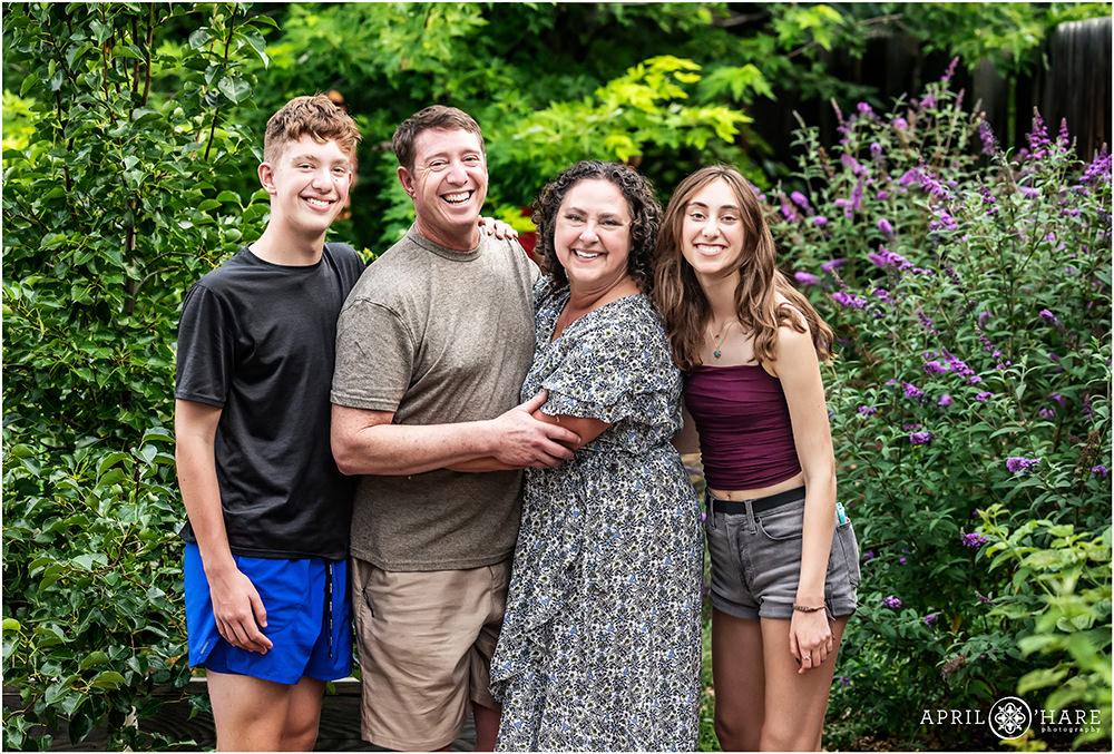 Family of four pose in the garden at their backyard bar mitzvah party during summer