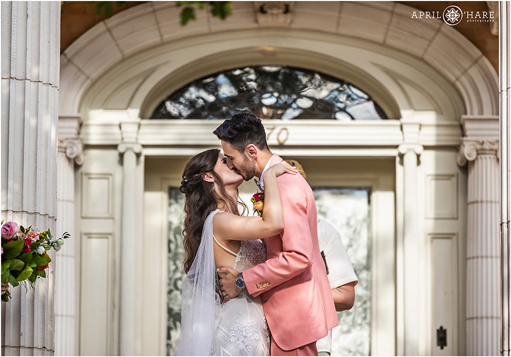 Bride and groom kiss at the end of their wedding ceremony on the stairs of the Grant-Humphreys Mansion in Denver CO