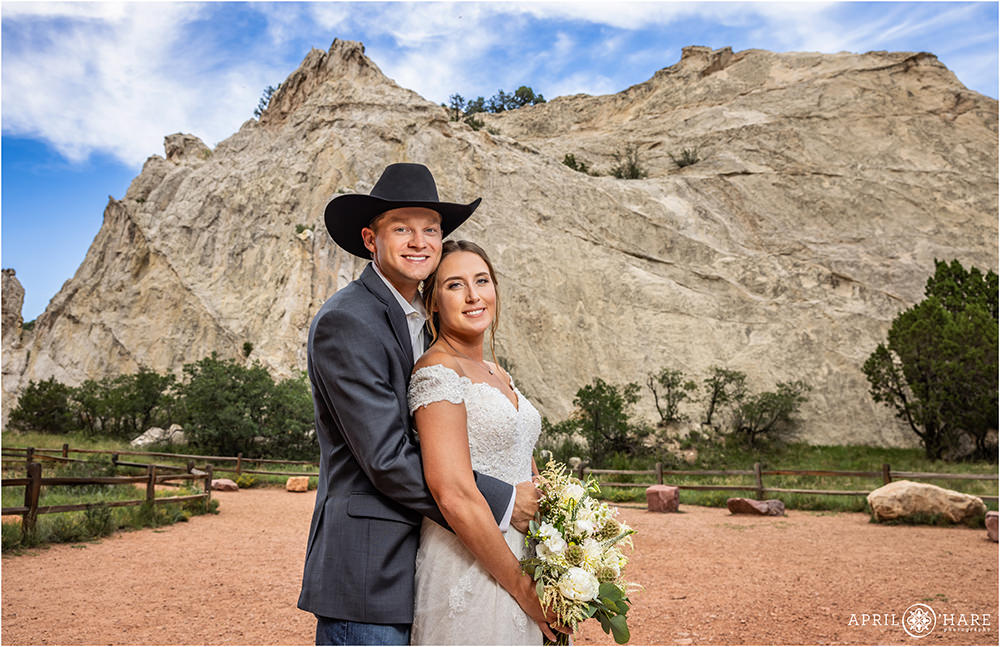 Bride and groom pose for a portrait with a white rock backdrop after their summer wedding ceremony at Jaycee Plaza in Garden of the Gods