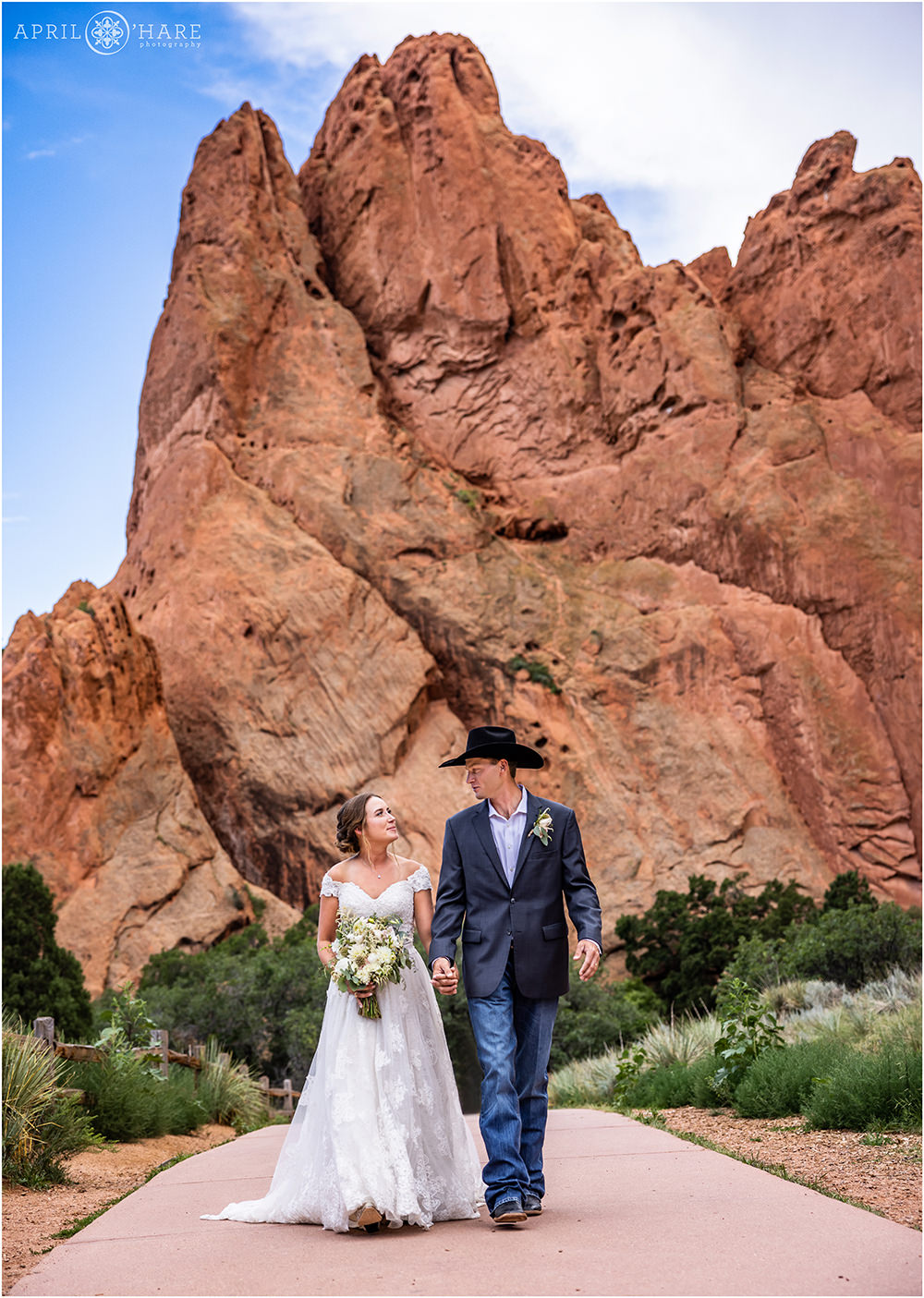 Bride and groom walk hand in hand on the main sidewalk at Garden of the Gods in Colorado Springs