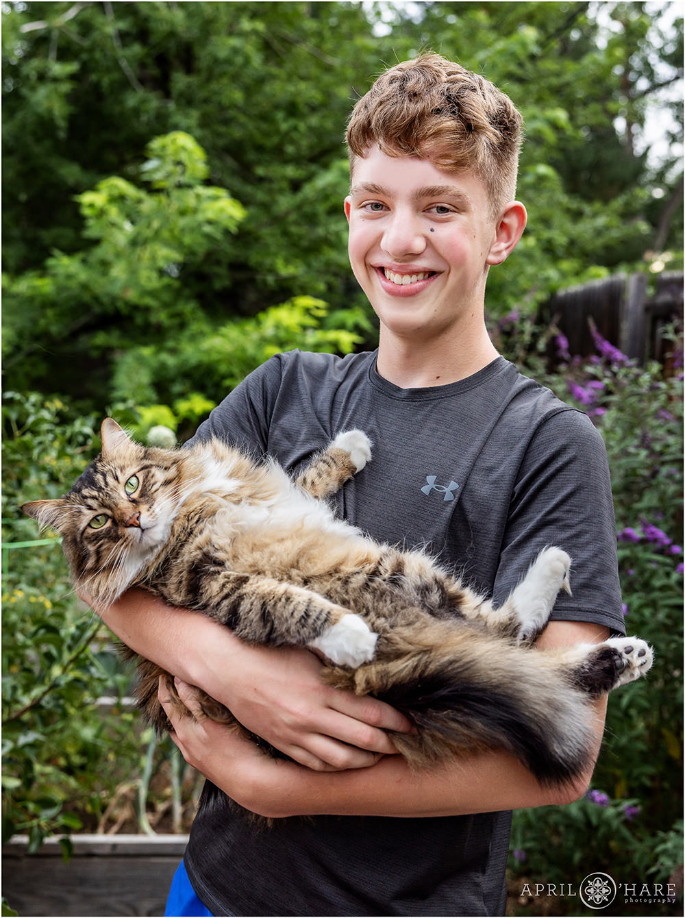Bar mitzvah boy holds his large fluffy cat at his backyard bar mitzvah in Colorado