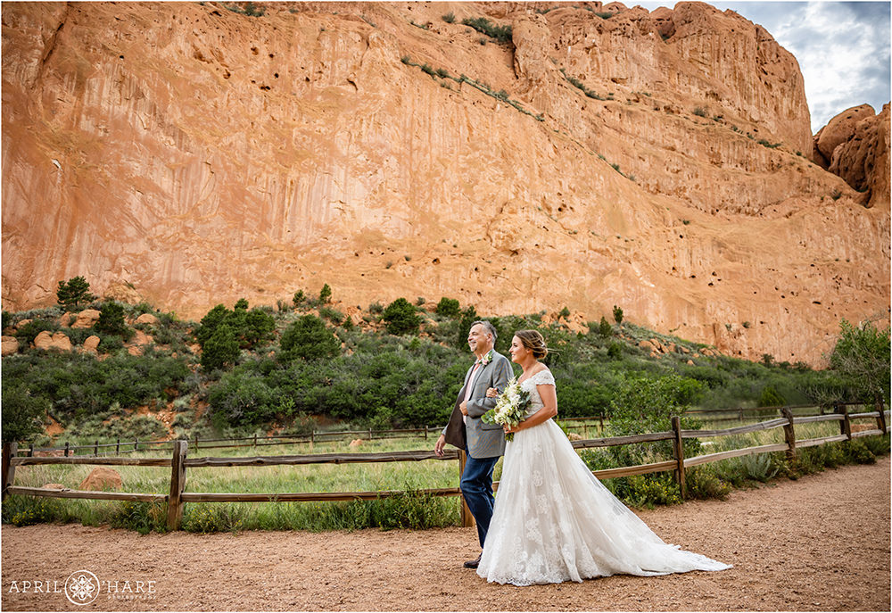 Bride walks with her dad down the aisle with gorgeous red rock backdrop at Garden of the Gods