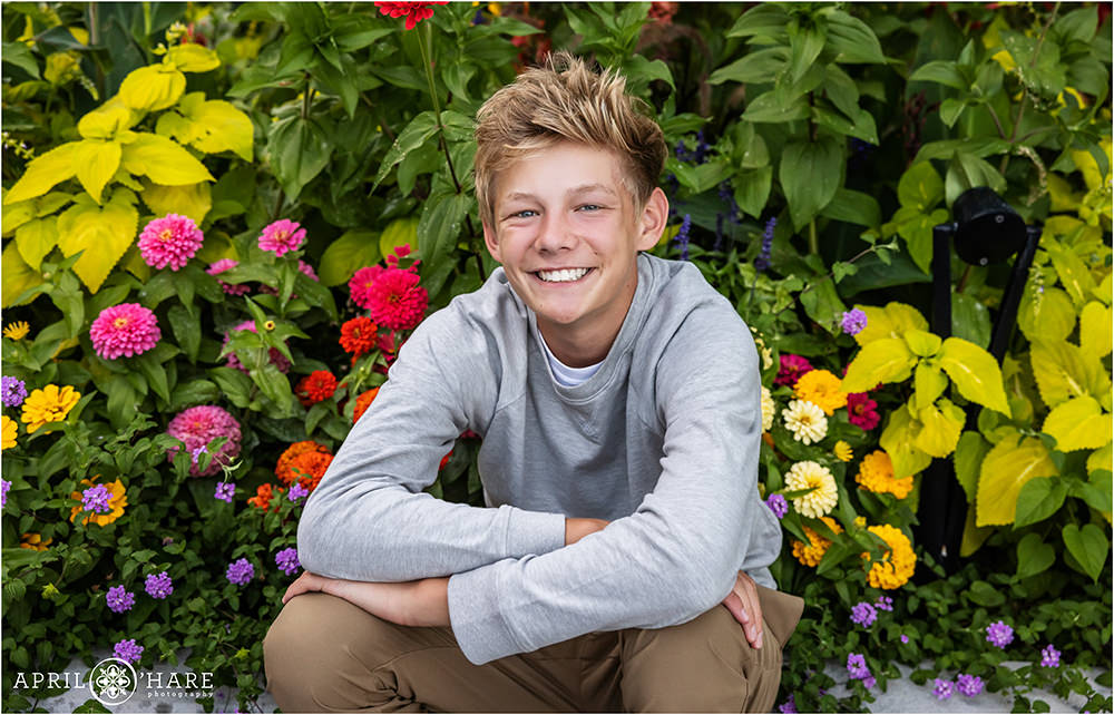 Teenage boy sits in a flower garden outside of Denver Botanic Gardens