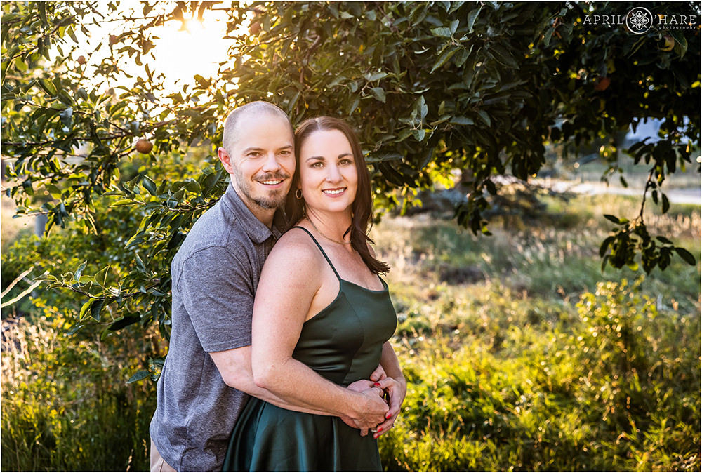 Cute couple photographed in front of a pretty apple tree at sunset at Heritage Lakewood Belmar Park