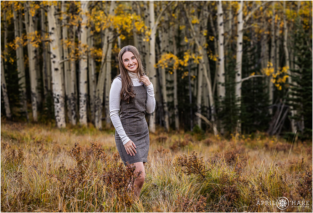 Gorgeous fall color high school senior in a mountain meadow with aspen grove backdrop