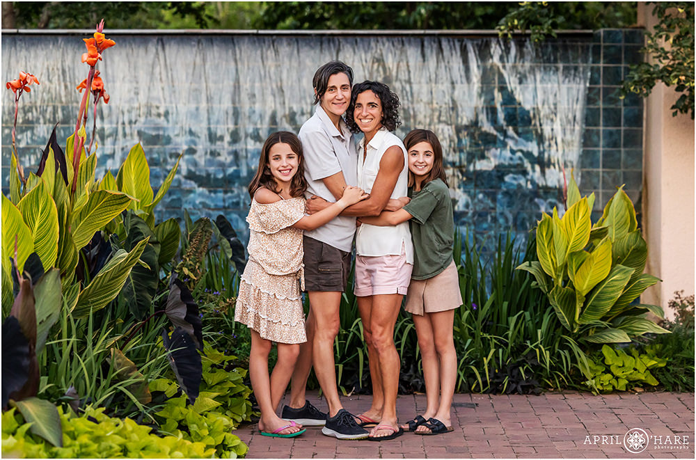 Sweet family photo at sunset with blue waterfall backdrop at Denver Botanic Gardens