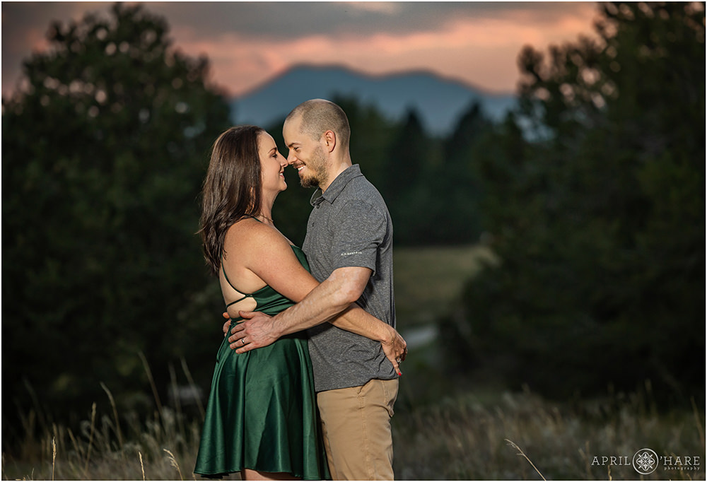 Couple snuggle each other at their sunset photo session with mountain backdrop at Belmar Park