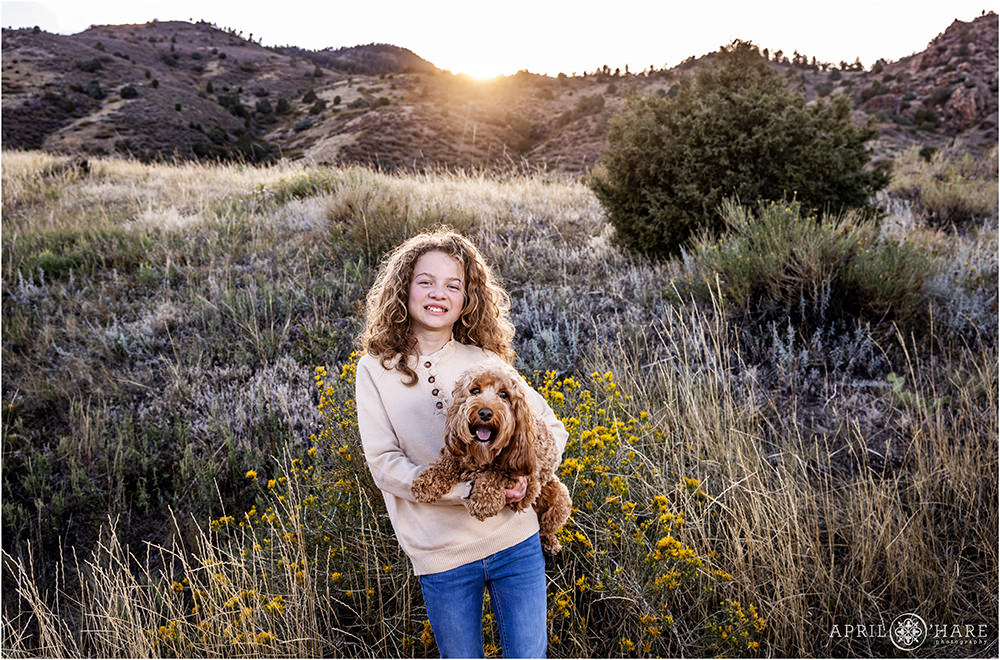 Cute photo of a young girl holding her cavapoo dog at East Mount Falcon Trailhead in Morrison CO