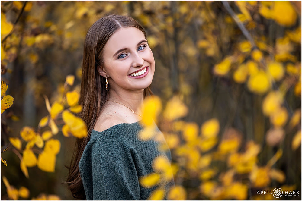 Stunning high school senior girl framed by fall foliage on Squaw Pass Road in Colorado