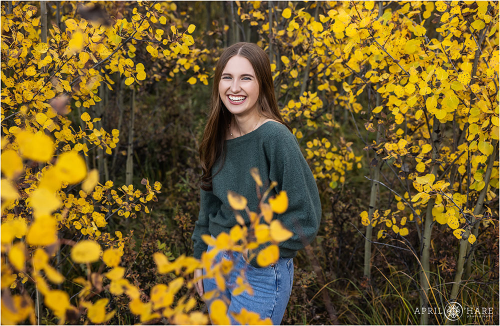 Senior girl laughs as she's photographed in the fall color on Squaw Pass Road in Evergreen CO