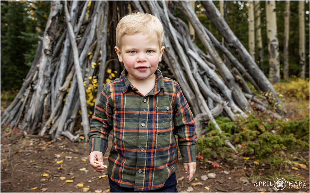Toddler boy wearing a cute green flannel shirt in the woods of Colorado during fall