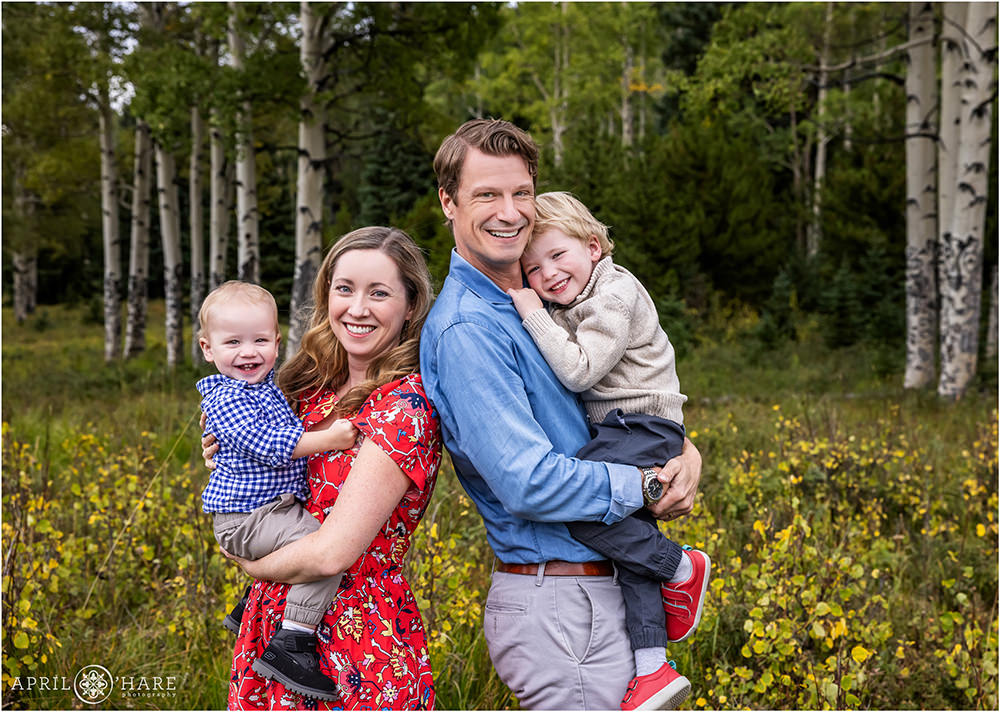 A sweet photo of a family of four with two young sons in a pretty mountain meadow in Evergreen Colorado
