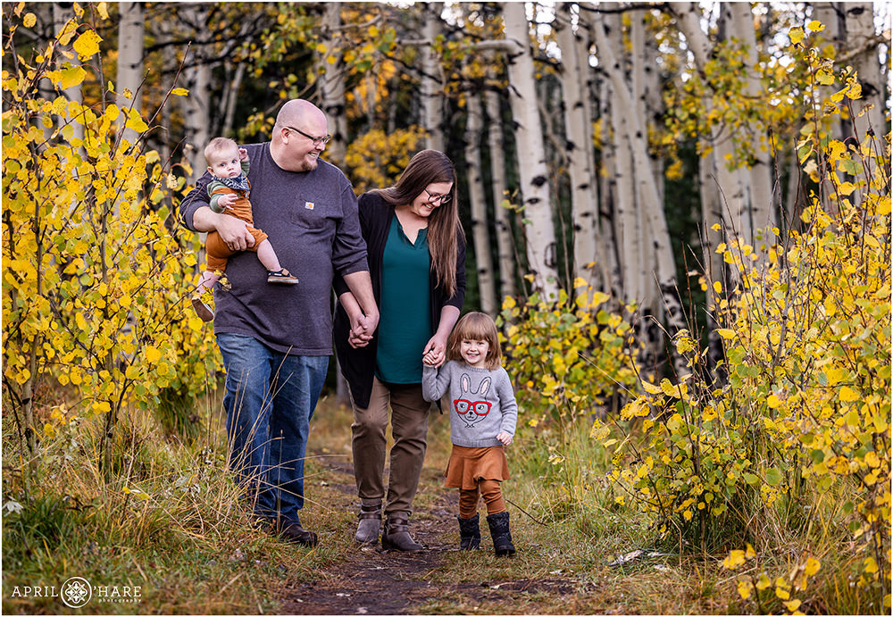 Sweet family of four take a walk in the woods with lots of fall color surrounding them