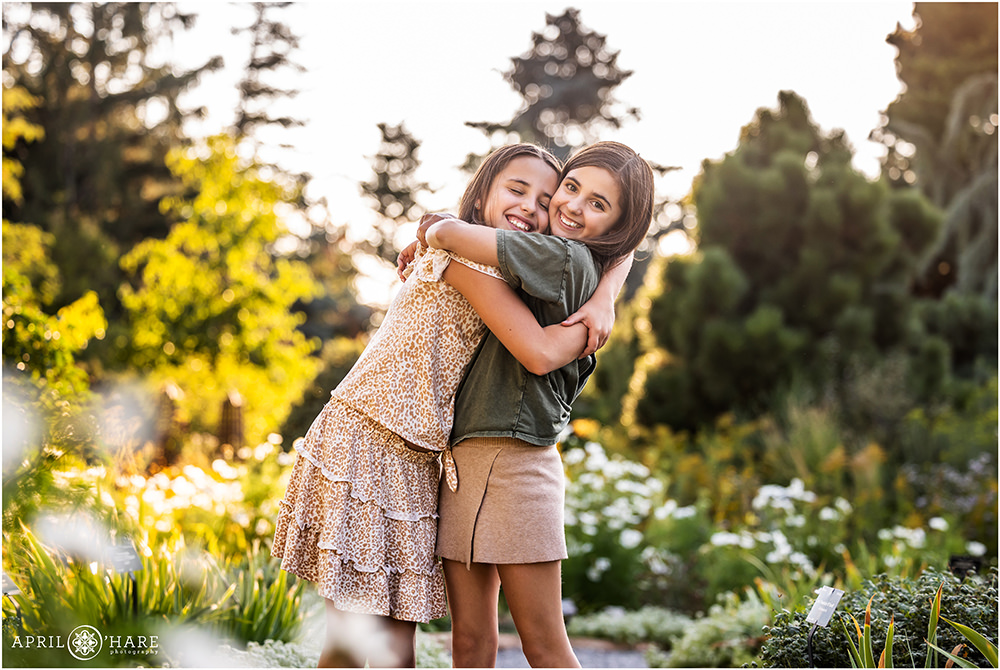 Two sisters hug each other in a pretty garden with white flowers at Denver Botanic Gardens