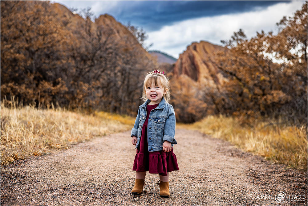 Adorable Toddler Smiles at her parents on the path at Roxborough State Park